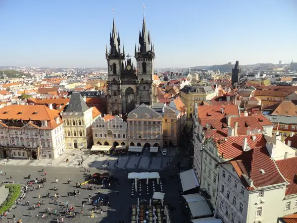 Blick über die Dächer der **Prag Stadt** mit der Teynkirche im Zentrum. Menschen beleben den Platz.
