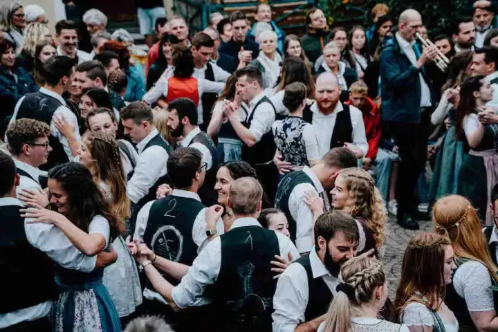 Menschen in Tracht tanzen ausgelassen. Ein Mann spielt Trompete. Hier ist heute Kirchweih in Franken!